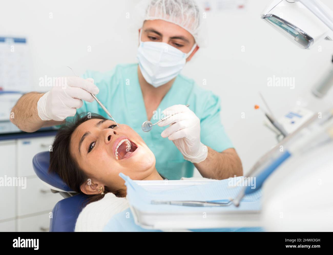 Dentist man examining a latin female patient teeth Stock Photo Alamy