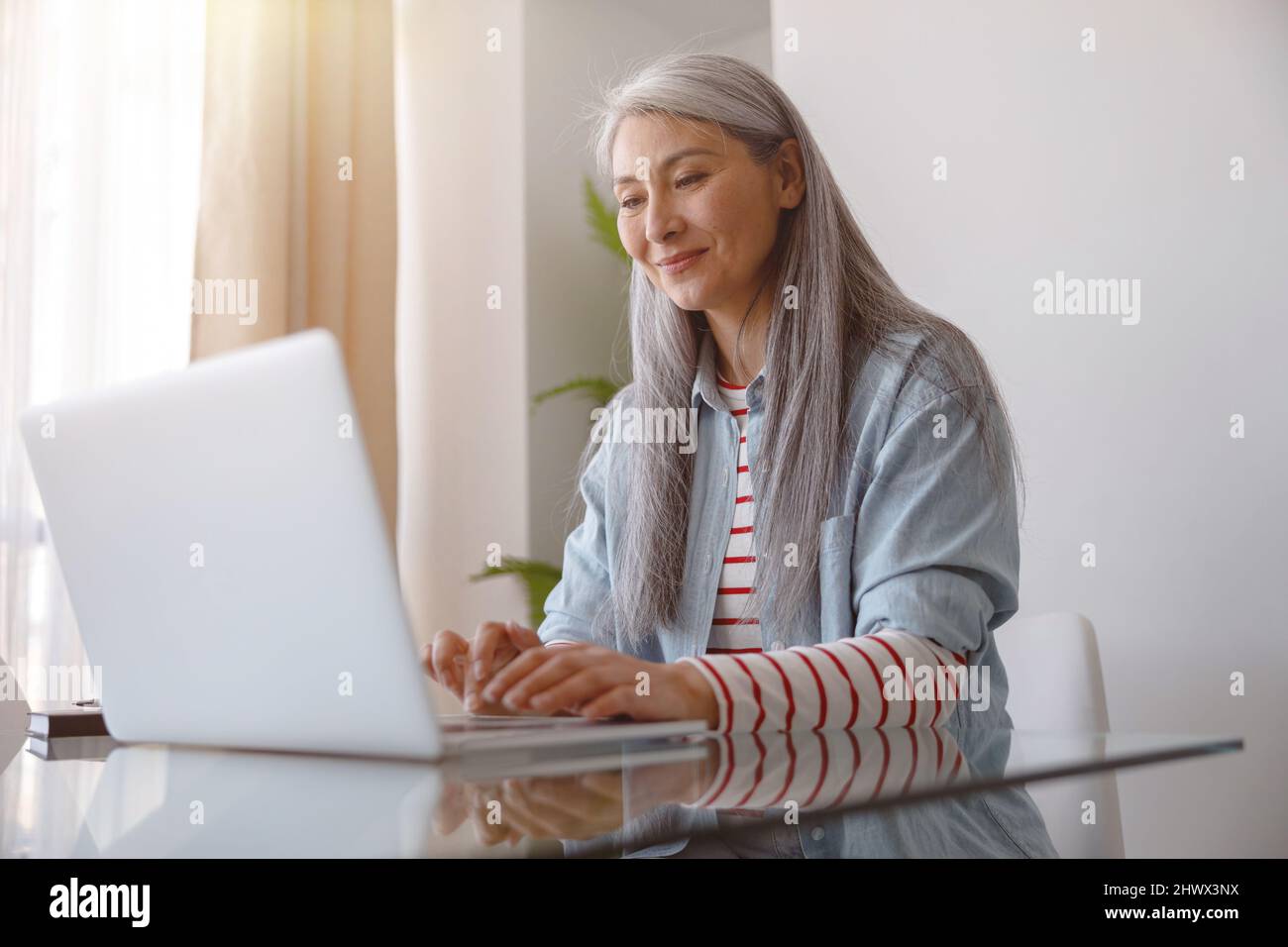 Joyful woman working on notebook at home Stock Photo