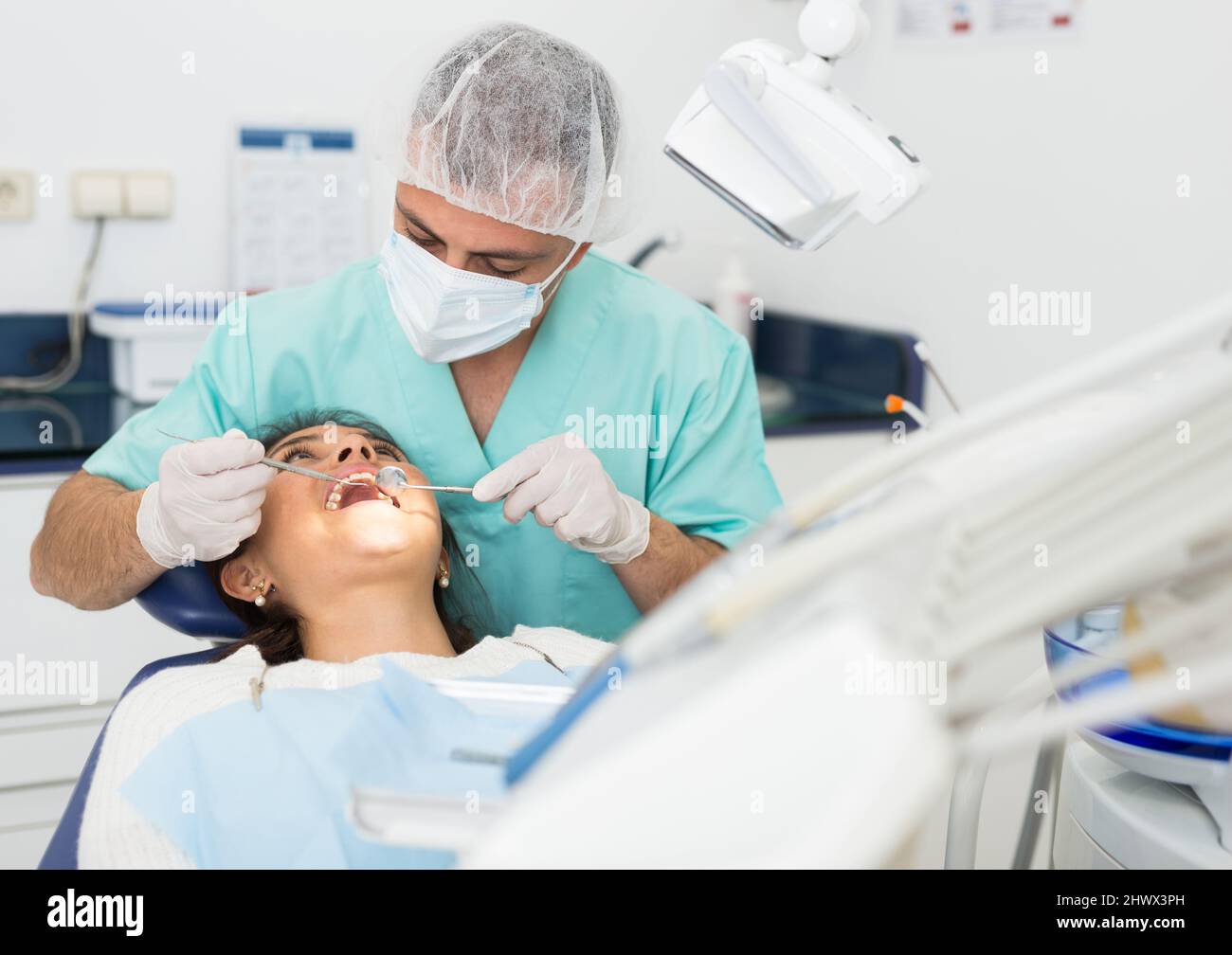 Dentist man examining a latin female patient teeth Stock Photo Alamy