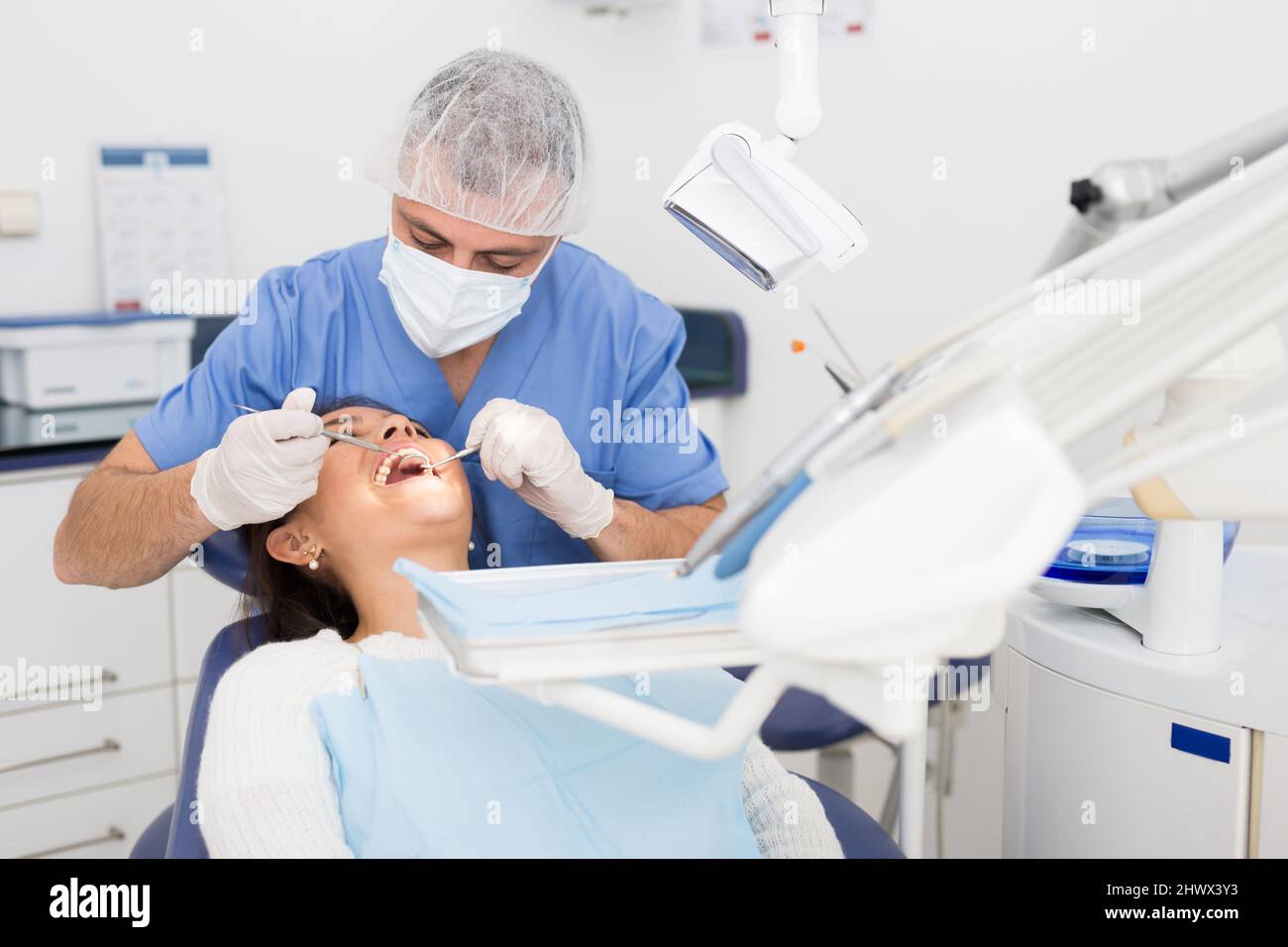 Dentist man examining a latin female patient teeth Stock Photo Alamy
