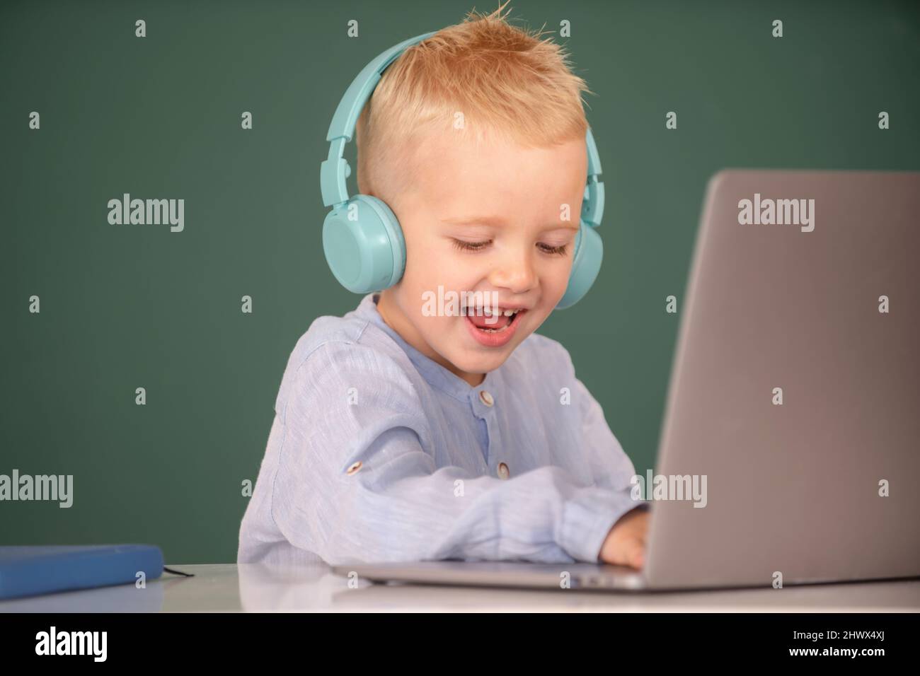 Happy child boy in headphones using a laptop and study online with ...