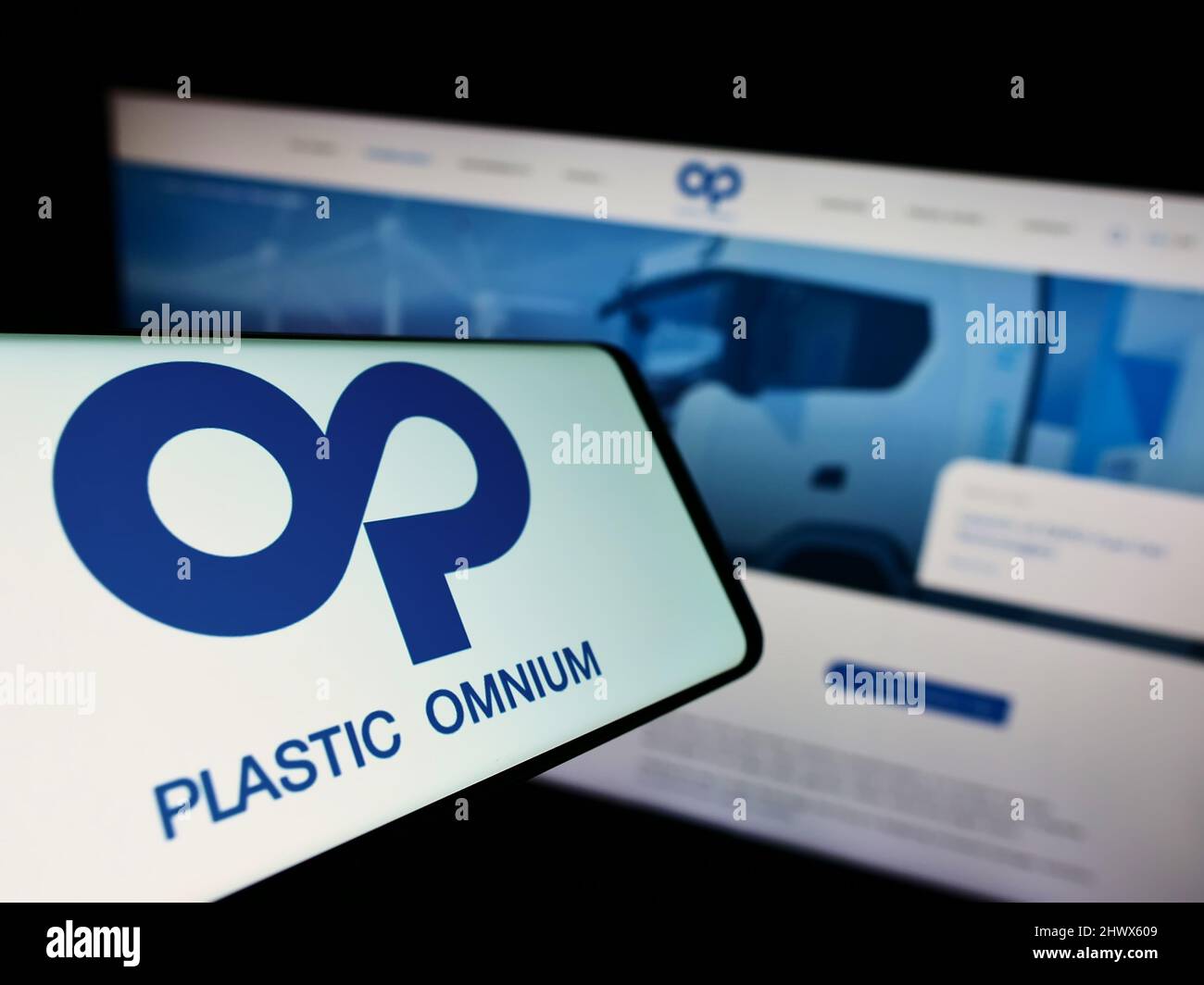 Cellphone with logo of French company Compagnie Plastic Omnium SA on screen in front of business website. Focus on center-right of phone display. Stock Photo