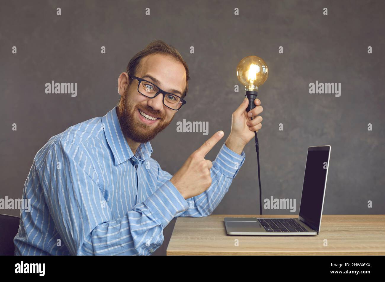 Young happy business man freelancer with lightbulb front of laptop at desk Stock Photo