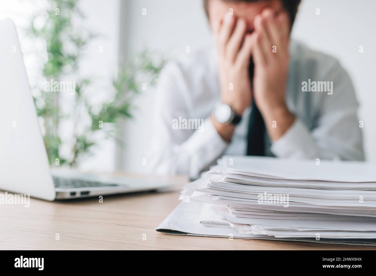 Exhausted businessman overloaded with work in office, selective focus Stock Photo