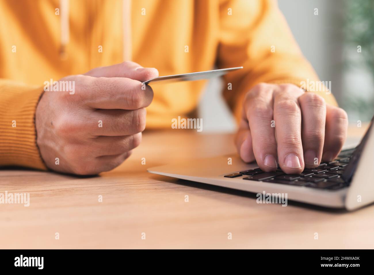 Online shopping from home, closeup of male hands using laptop and debit card to purchase on internet, selective focus Stock Photo