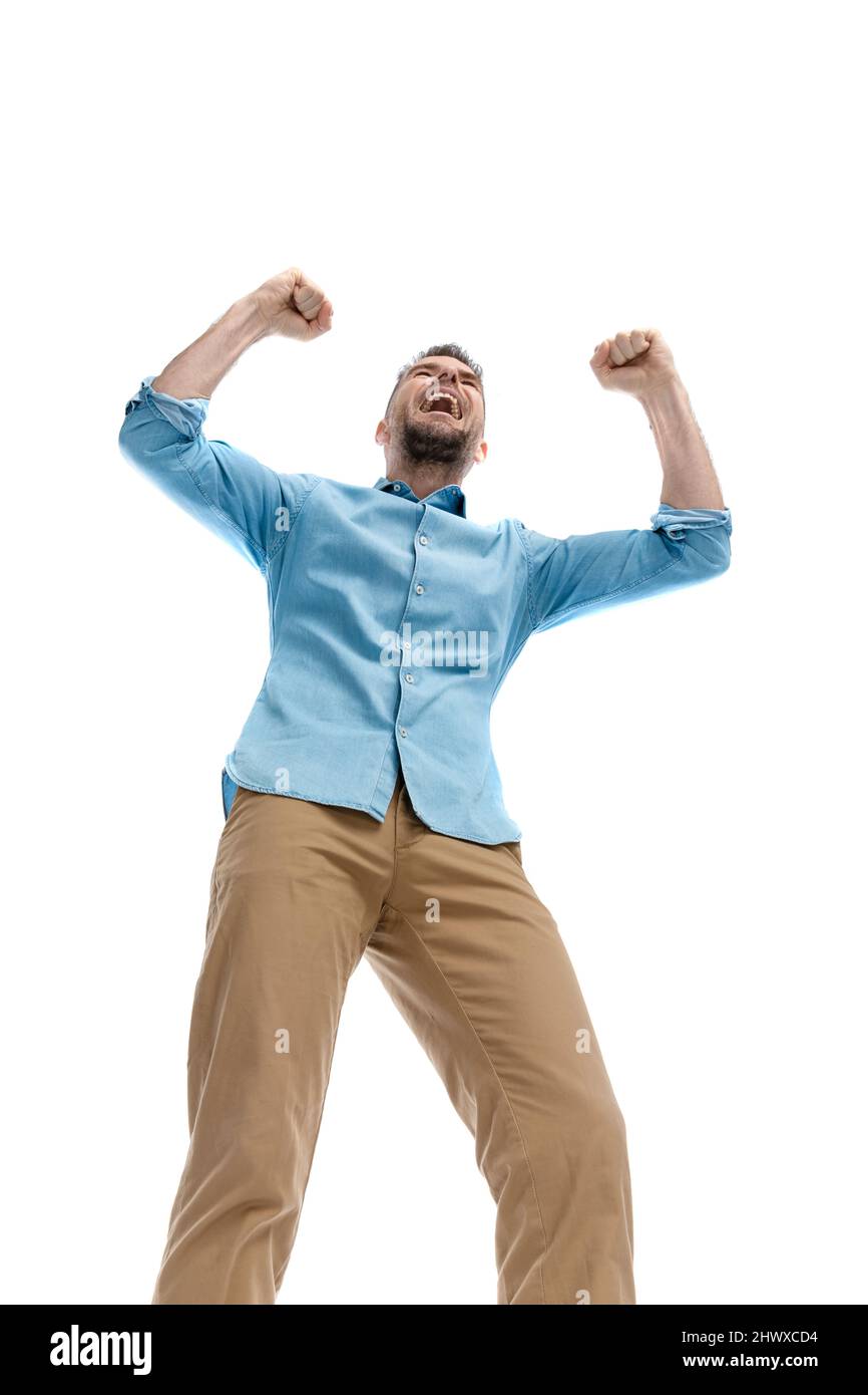 low angle view surprising enthusiastic young guy with arms in the air, enjoying the victory and laughing on white background Stock Photo