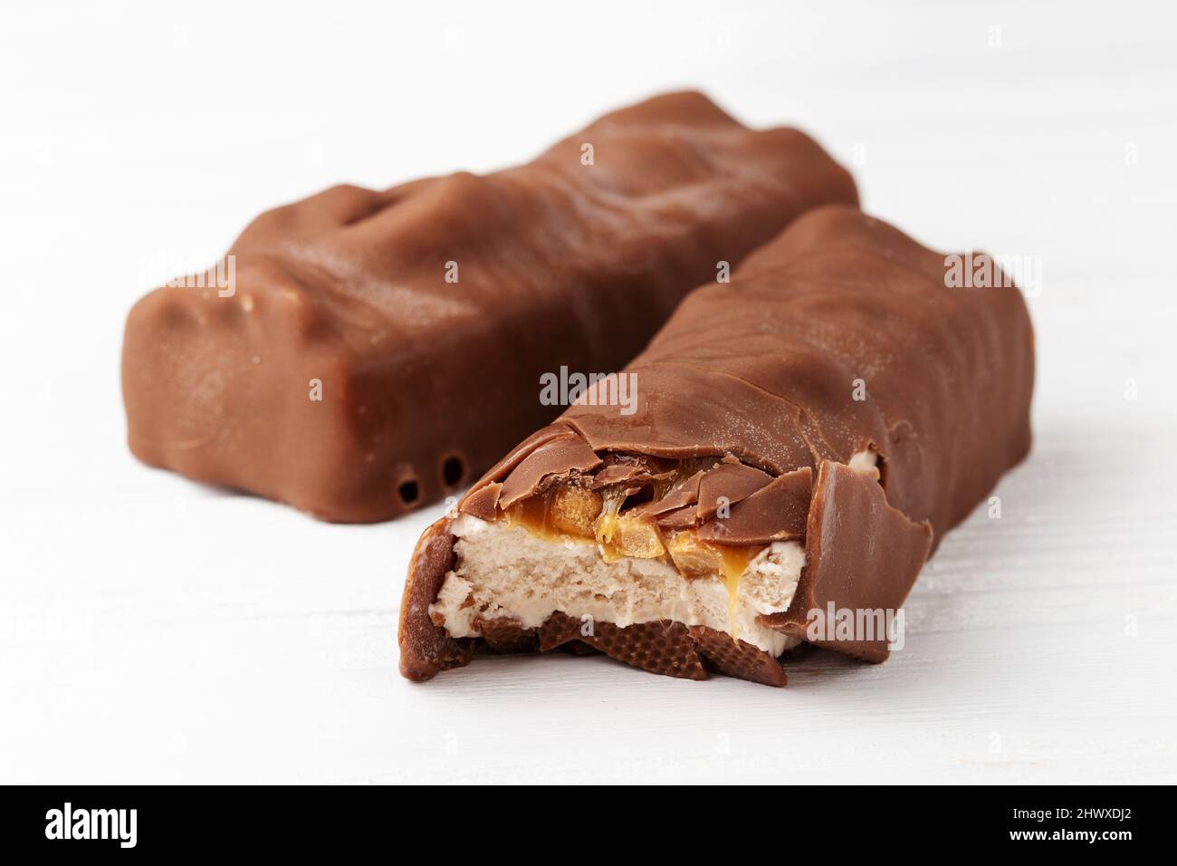 Two chocolate ice cream bars with caramel and peanuts on white background close up macro shot Stock Photo