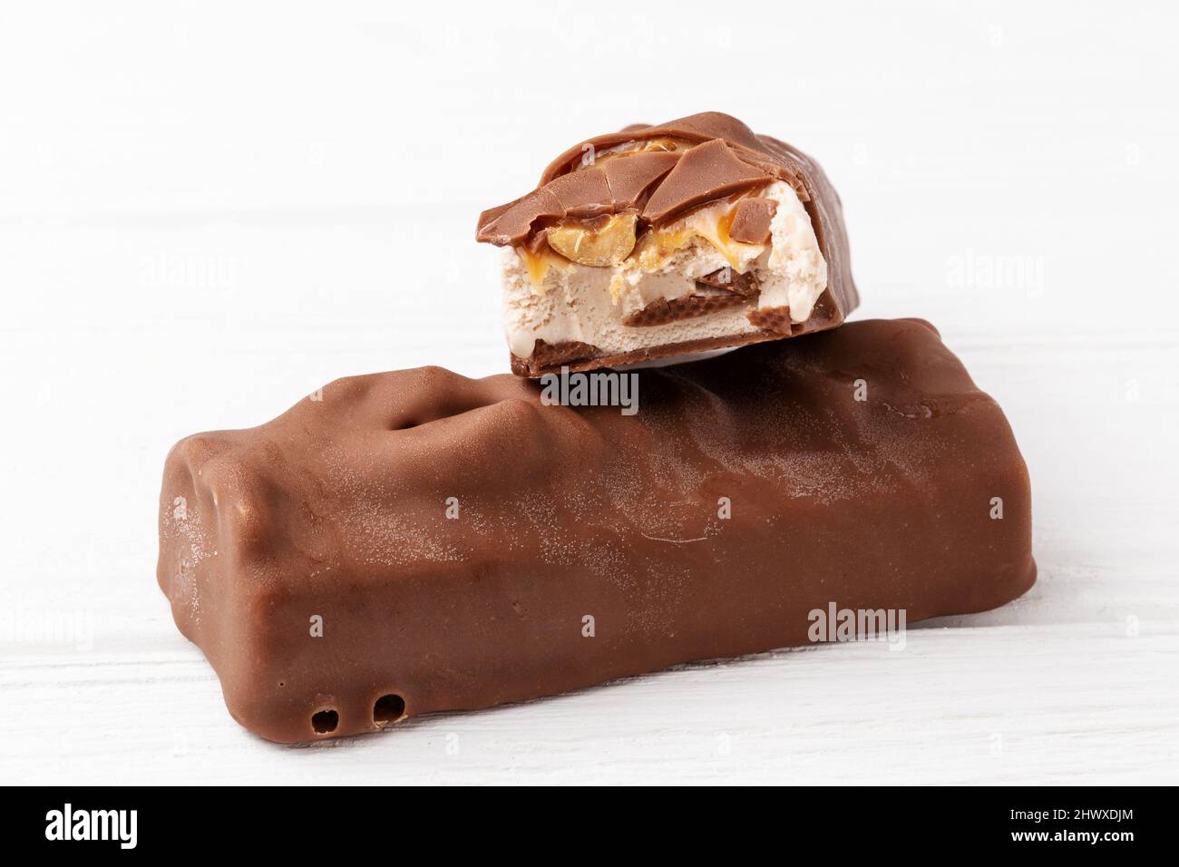 Two chocolate ice cream bars with caramel and peanuts on white background close up macro shot Stock Photo