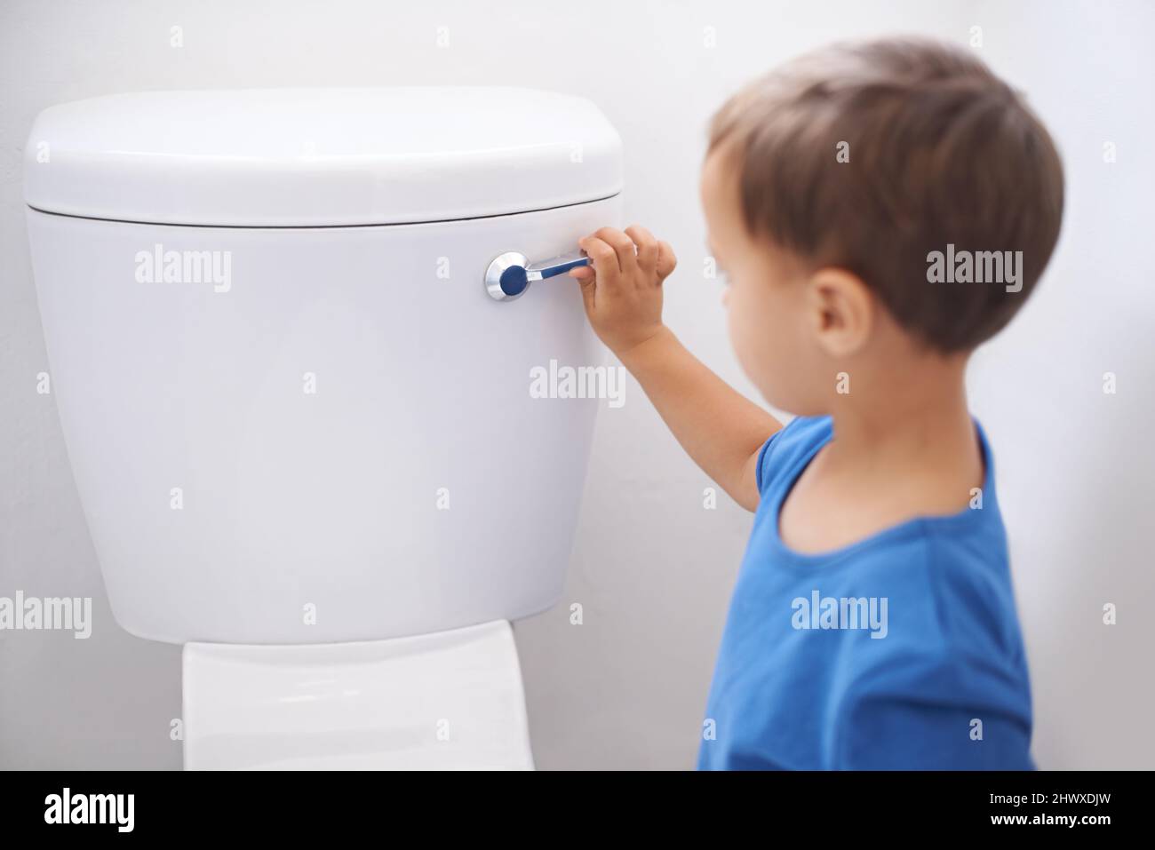 All done. Shot of a cute young boy flushing a toilet. Stock Photo