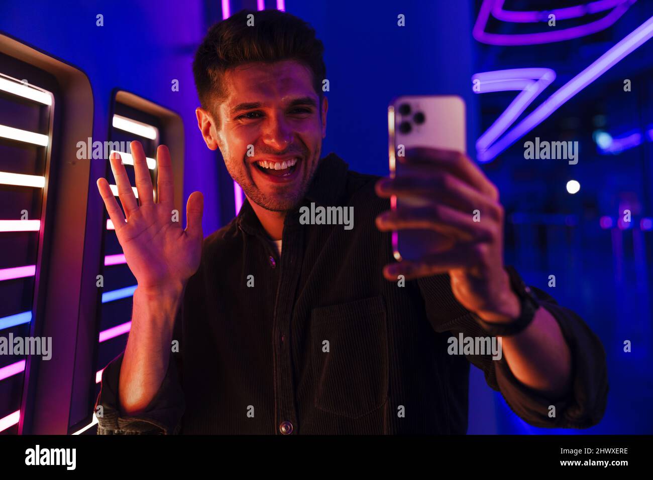 Young bristle man gesturing while taking selfie photo on mobile phone indoors Stock Photo