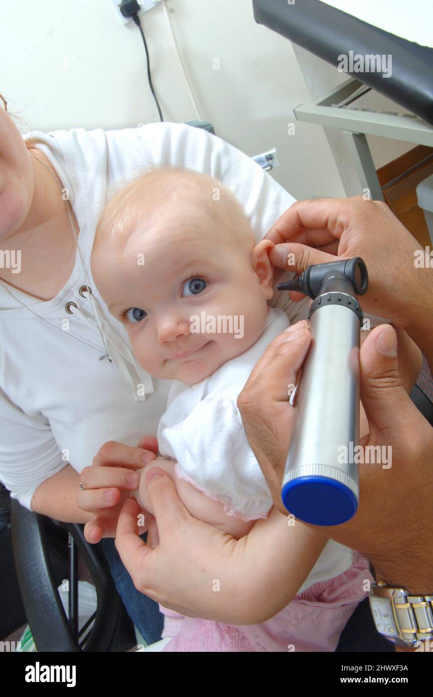 A GP uses an otoscope to examine the inside of a baby's ear.(MODEL