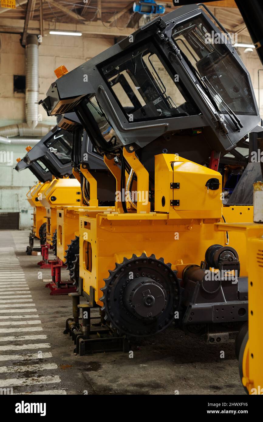 Several huge construction machines of yellow color standing in row on ...