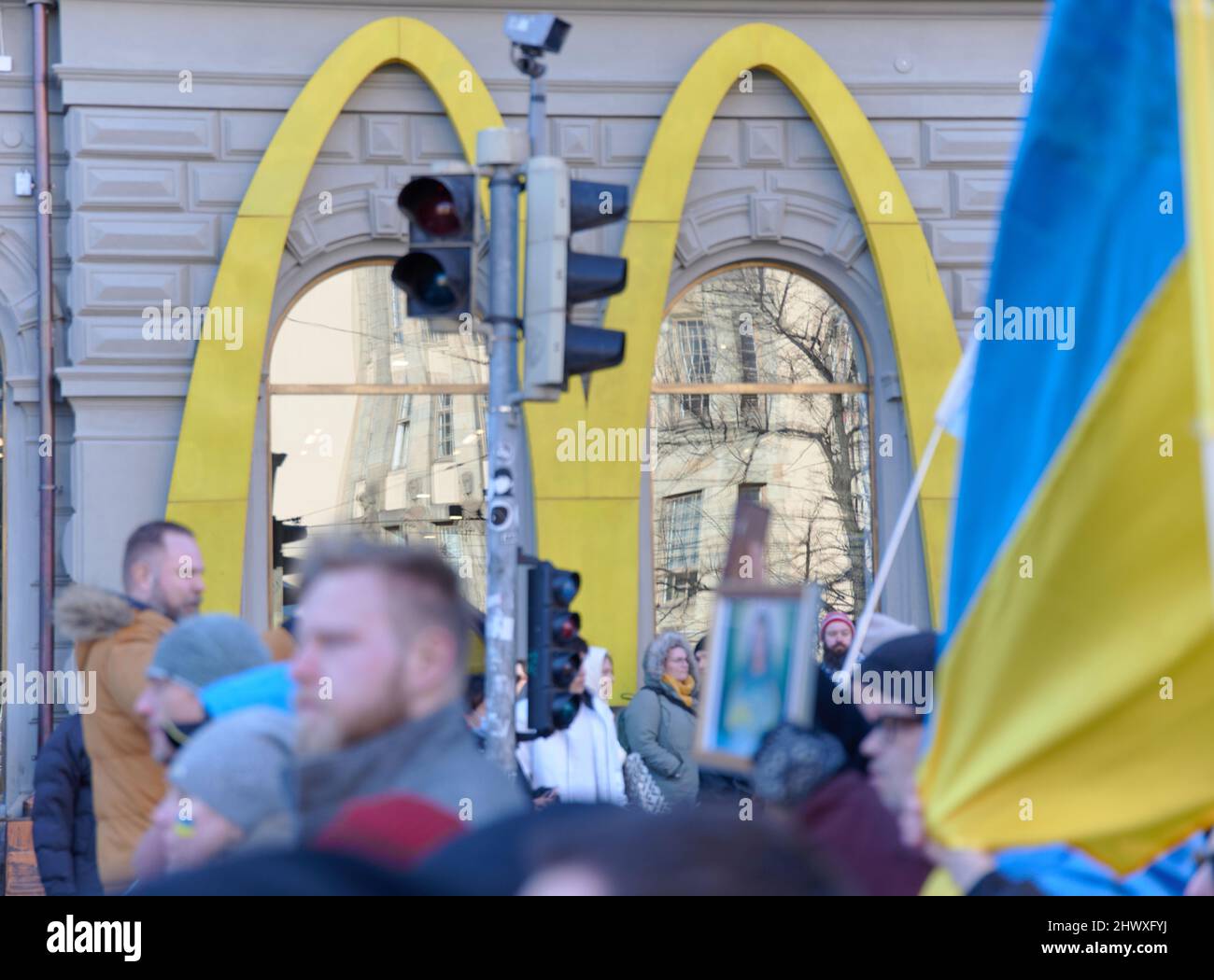 Helsinki, Finland - March 5, 2022: Yellow Mcdonald’s Golden Arches logo on the side of the building with a rally against Russia’s military actions and Stock Photo