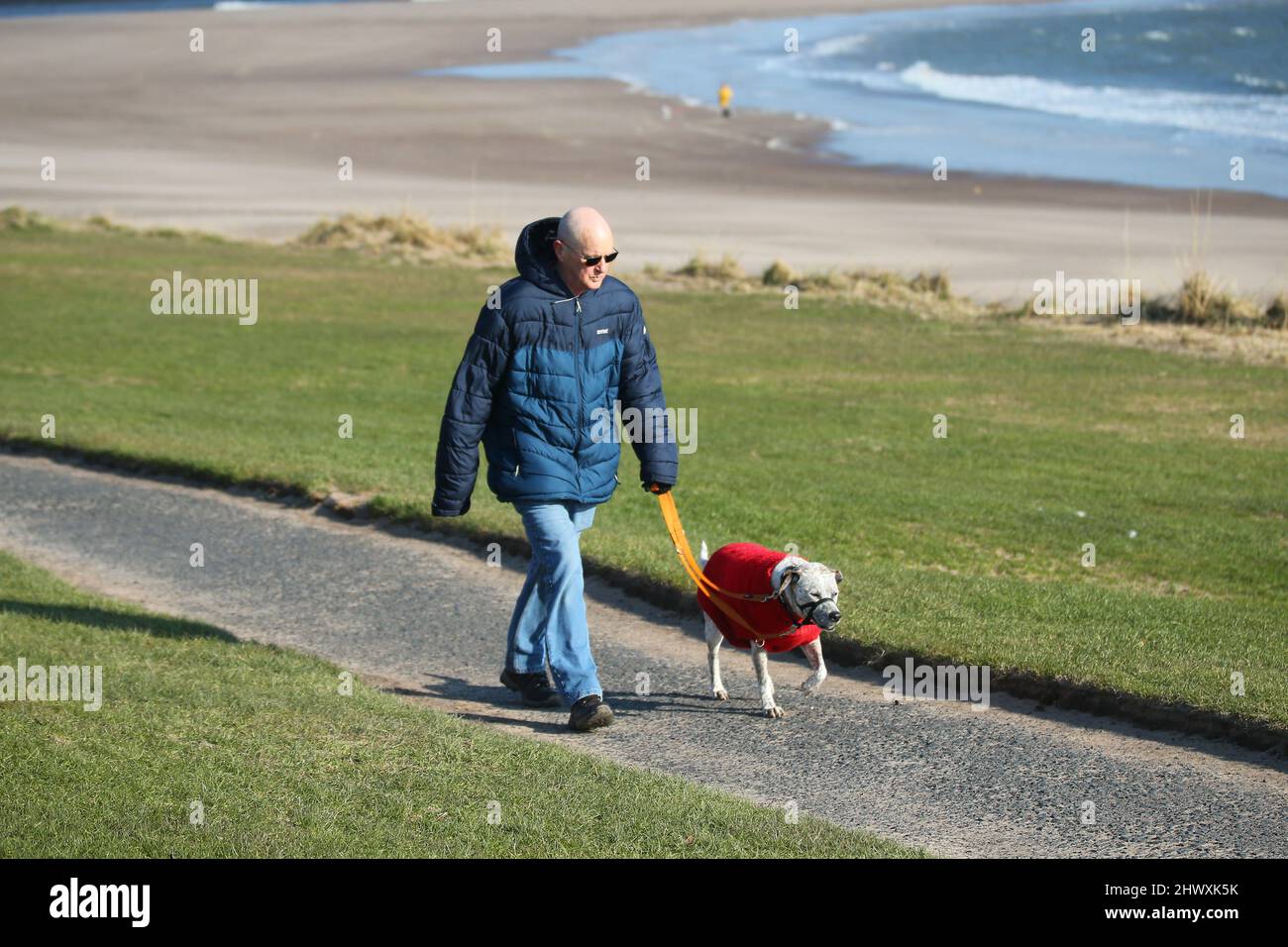 Berwick upon Tweed, UK, 8th March, 2022. UK Weather: Bright sunshine with breezy conditions along the sea front as people go for their morning walk. Credit: Gary Learmonth Alamy / Live News Stock Photo