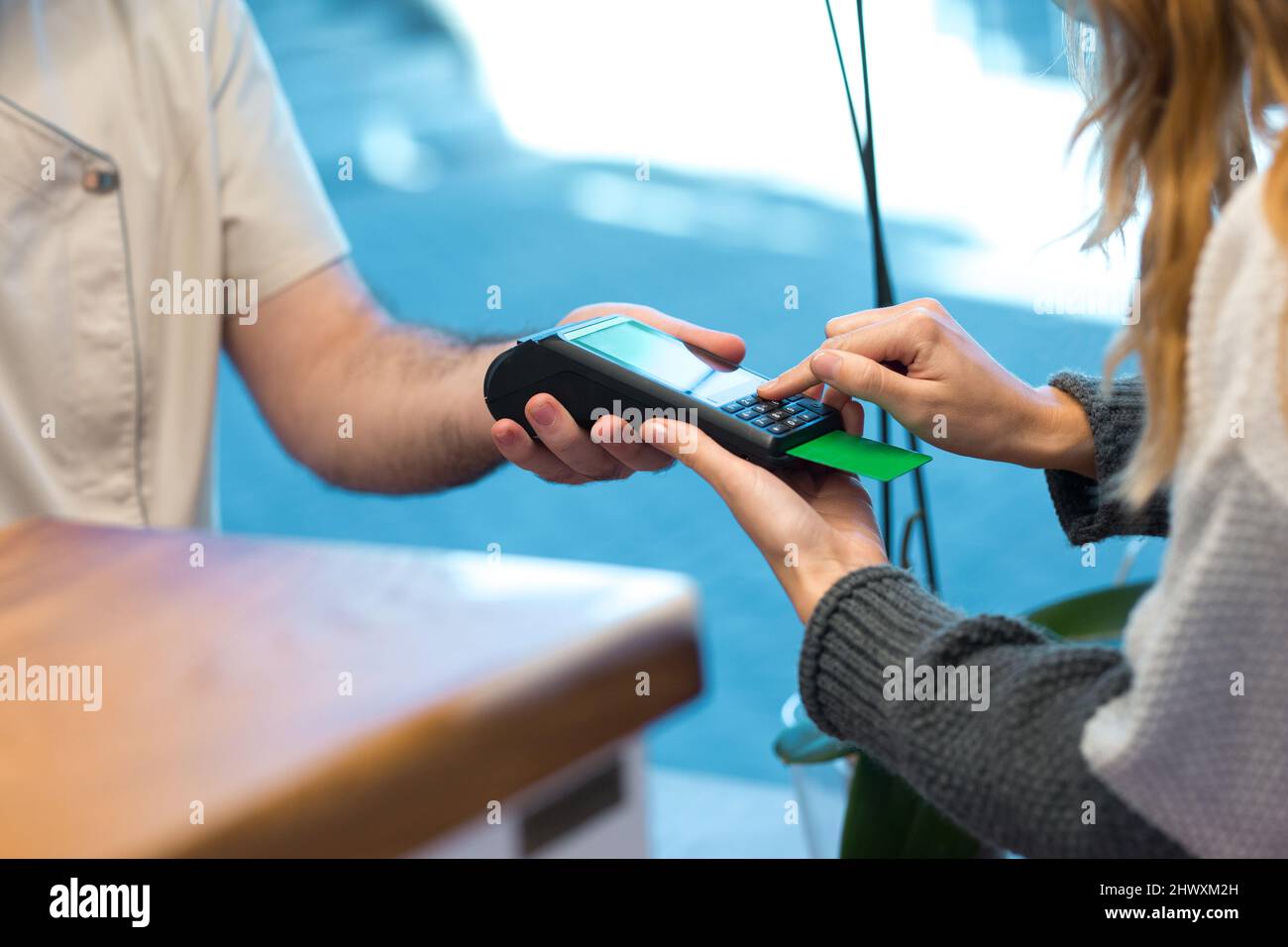 Woman entering bank card code on swiping machine in clinic Stock Photo