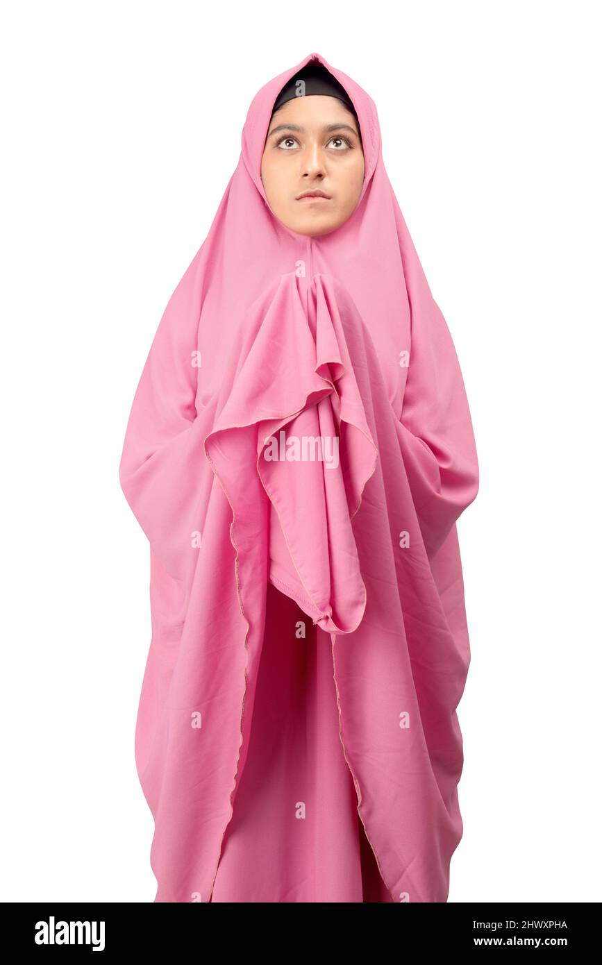 Asian Muslim woman in a veil standing while raised hands and praying ...
