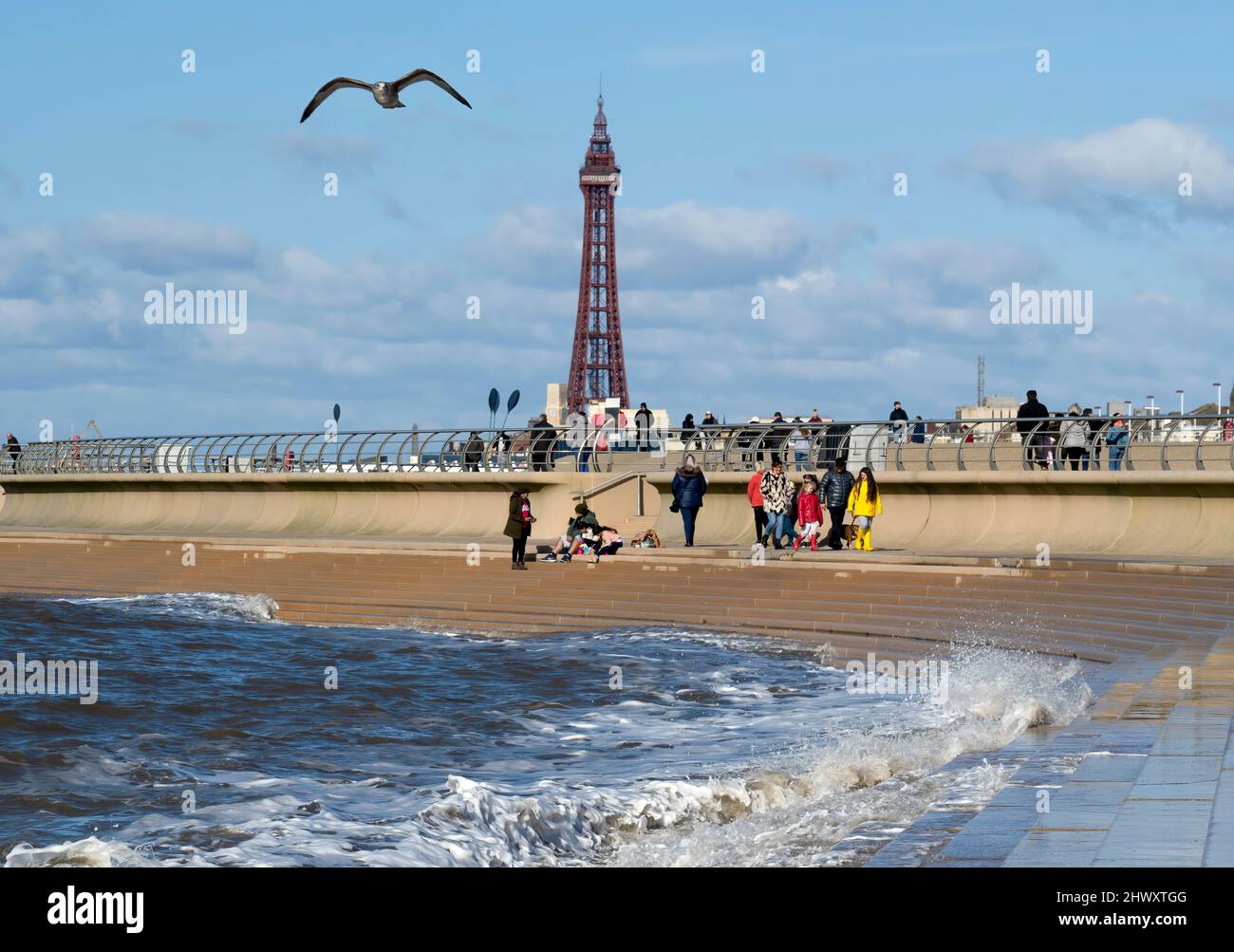 On a bright sunny day, holidaymakers hit the sandy beach under the shadow of the world famous Blackpool Tower in Blackpool, Lancashire, UK Stock Photo