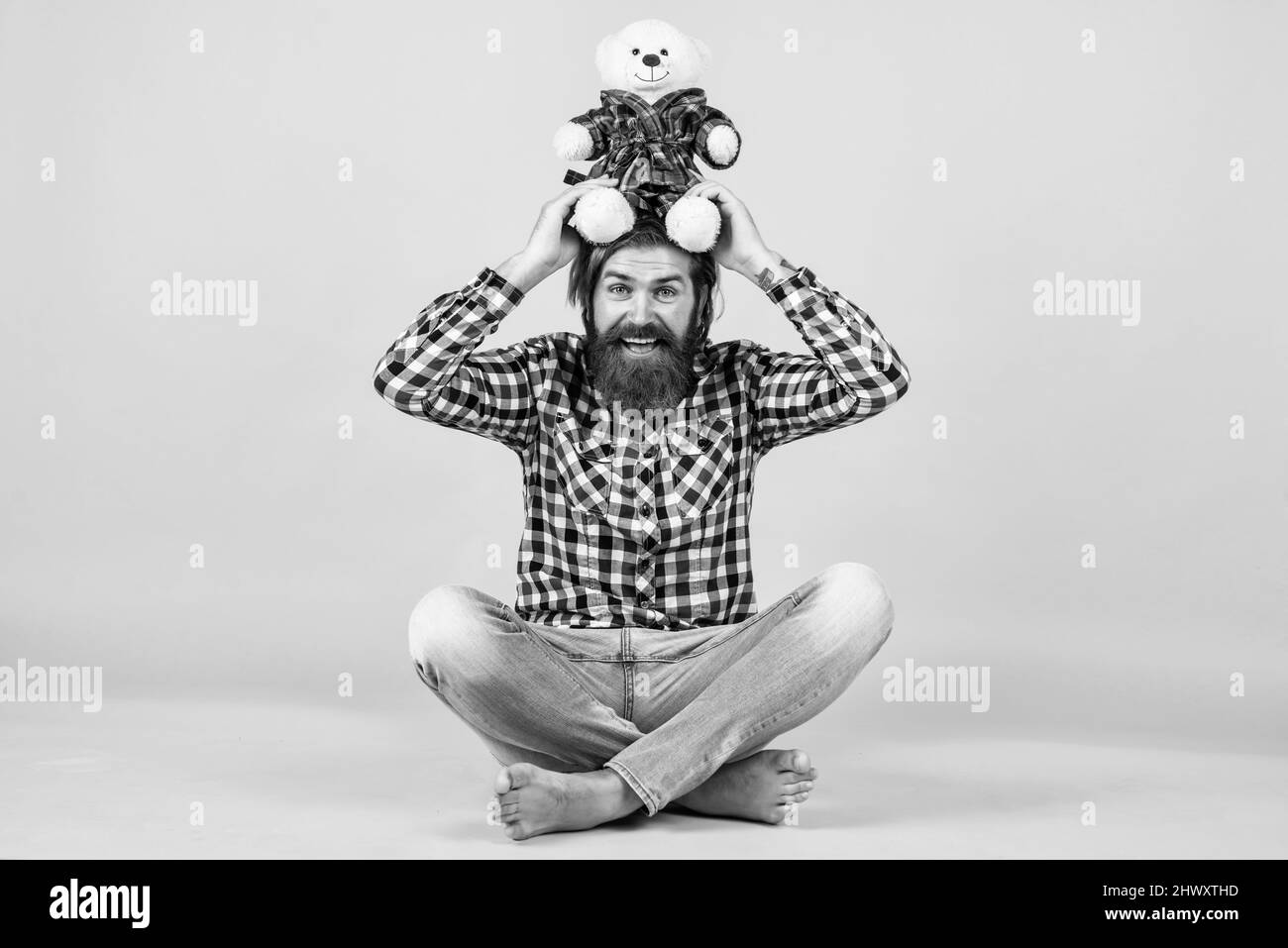 Caucasian mature hipster with trendy hairstyle in checkered shirt hold teddy bear toy, fun Stock Photo