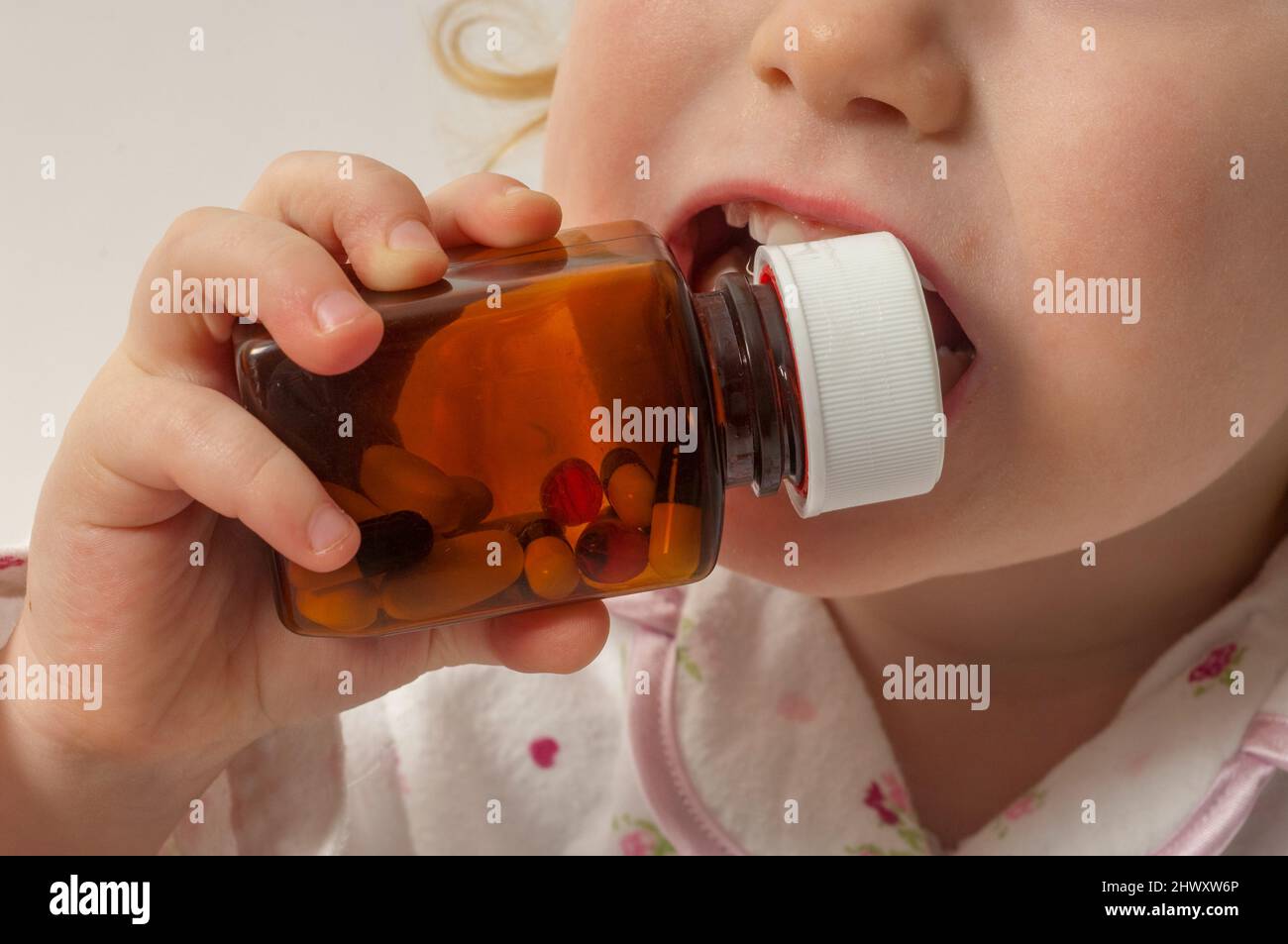 Child putting a sealed medicine bottle into her mouth (MODEL RELEASED