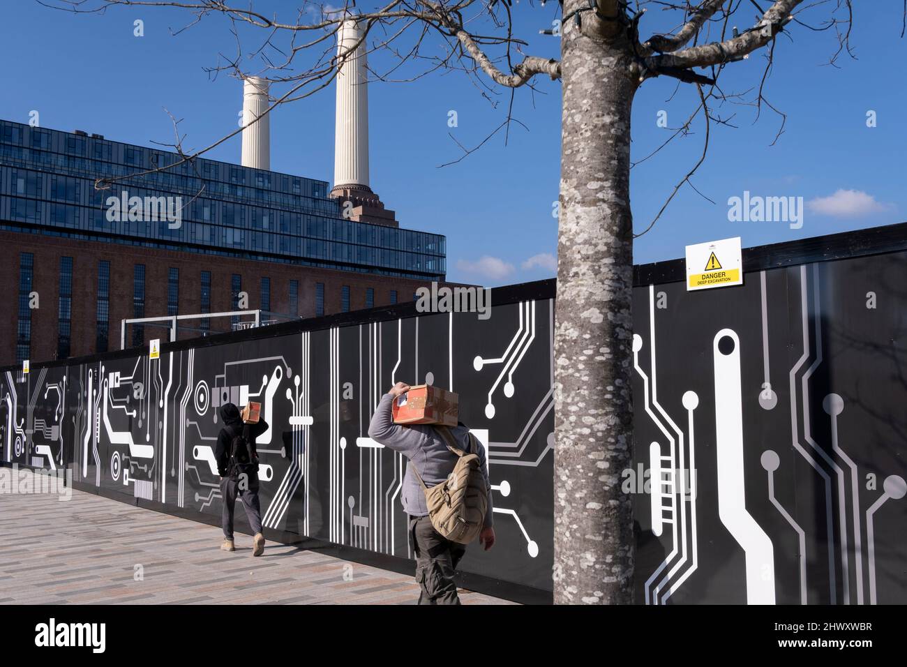 Two workmen carry similar boxes from the construction industry towards