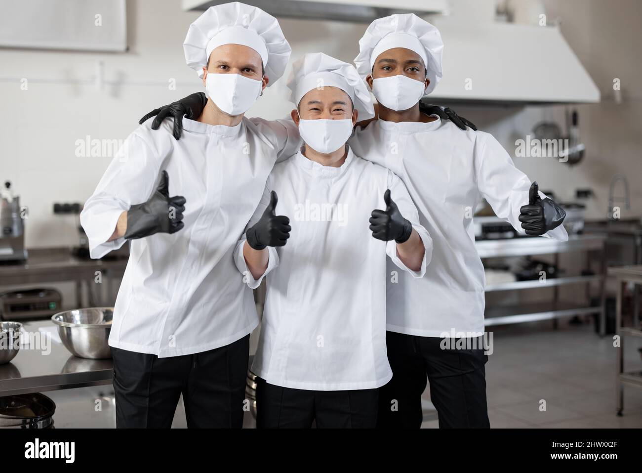 Portrait of multiracial team of three chefs standing together and
