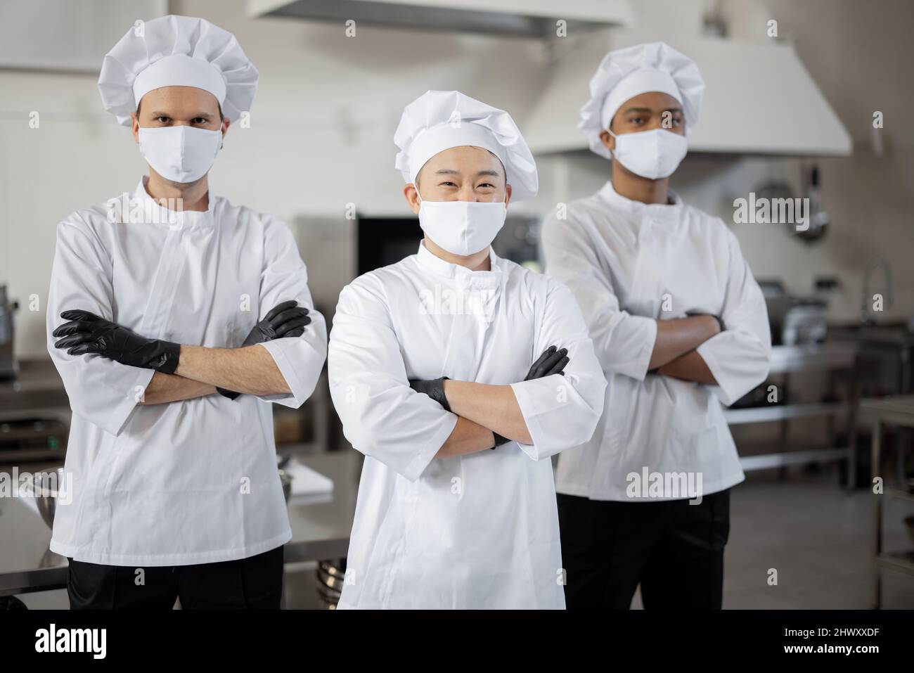 https://c8.alamy.com/comp/2HWXXDF/portrait-of-multiracial-team-of-three-chefs-standing-together-in-the-professional-kitchen-well-dressed-chefs-in-face-masks-and-protective-gloves-ready-for-a-job-new-normal-for-business-during-pandemic-2HWXXDF.jpg