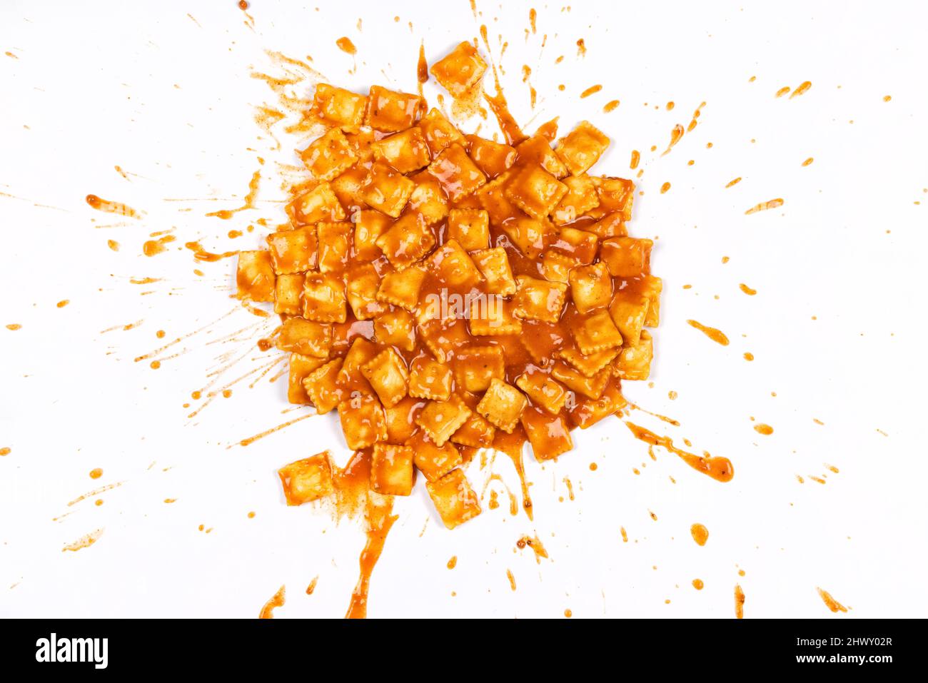 Ravioli in tomato sauce splattered on a white background. Stock Photo