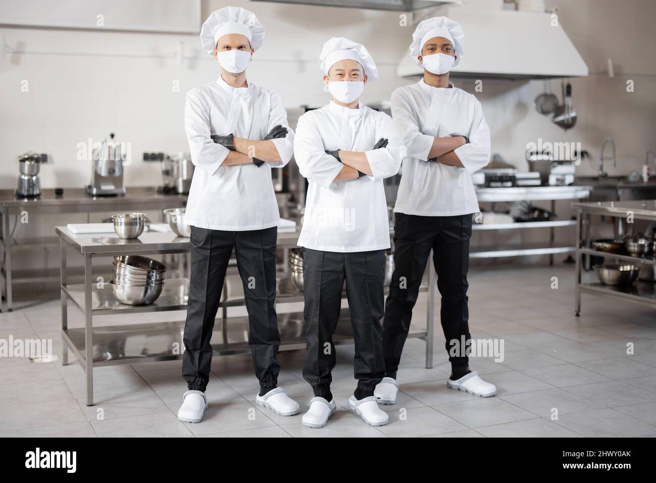 https://c8.alamy.com/comp/2HWY0AK/full-body-portrait-of-multiracial-team-of-three-chefs-standing-together-in-the-professional-kitchen-well-dressed-chefs-in-face-masks-and-protective-gloves-ready-for-a-job-new-normal-for-business-during-pandemic-2HWY0AK.jpg