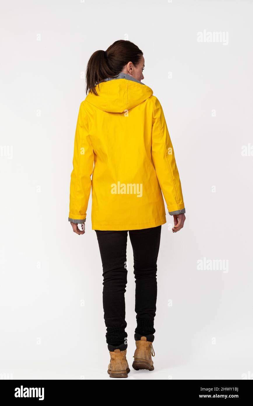 Rear view of a woman wearing a yellow coat, cut out. Stock Photo