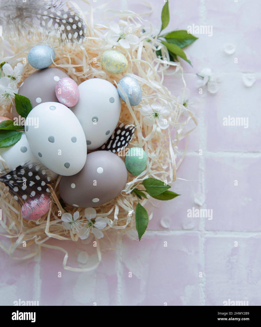 Easter eggs in straw nest on a pink tile background Stock Photo - Alamy