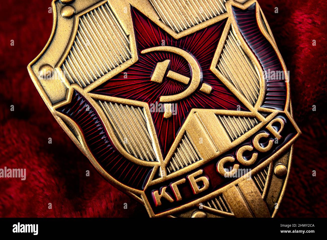 Secret service, intelligence agency, and espionage concept with macro close up on a cold war era KGB badge from the former USSR on red background Stock Photo