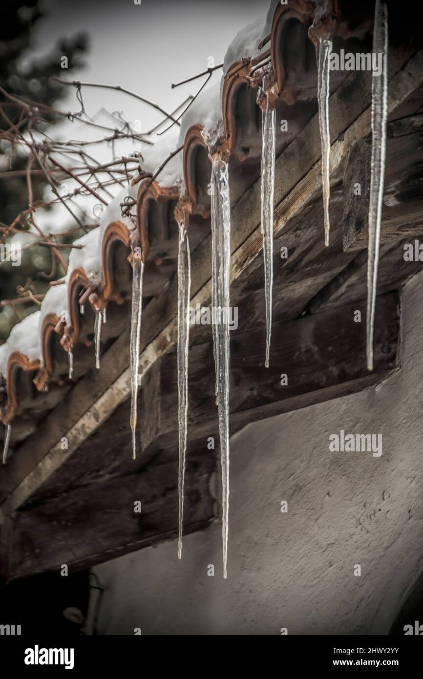 Large and sharp icicles hanging from a house roof Stock Photo