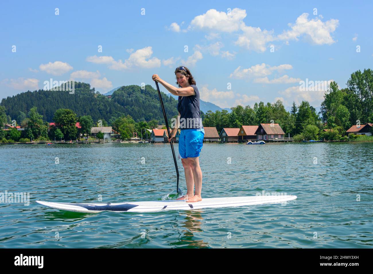 Sporty woman having fun on SUP board on the Alpsee in the Allgäu Stock ...