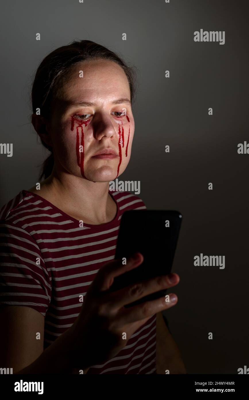 Woman reading news, crying blood tears. Pain, suffering or bullying Stock Photo