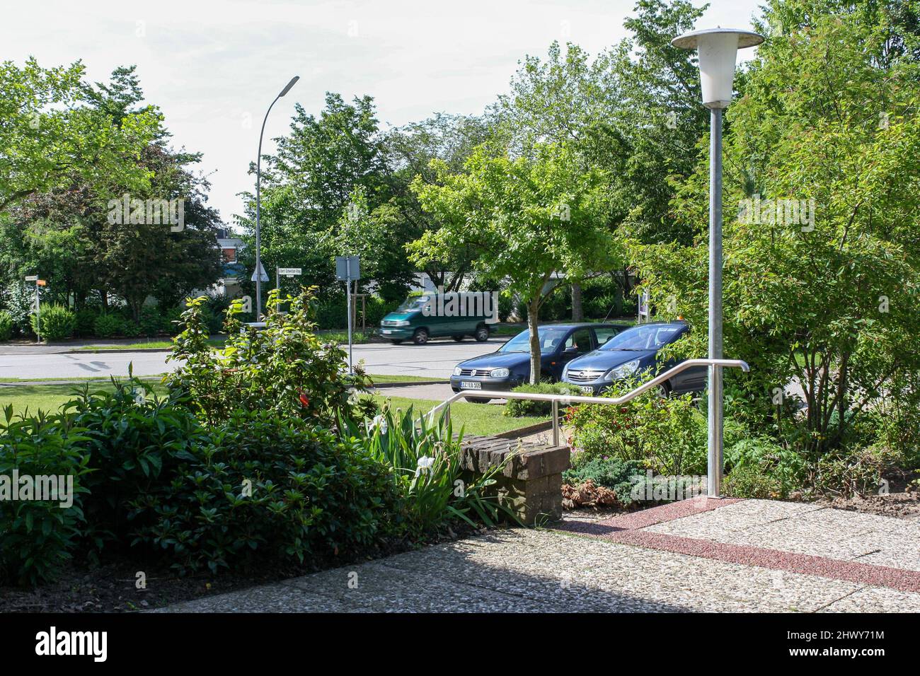 Itzehoe, Germany - Jun 2010: View of outdoor parking area in sunny summer with pavement walkway and trees foliage background. No people. Stock Photo