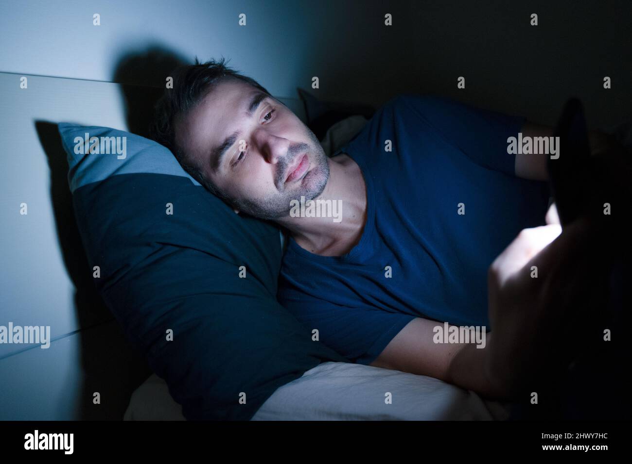 One relaxed man using phone in bed at night Stock Photo Alamy