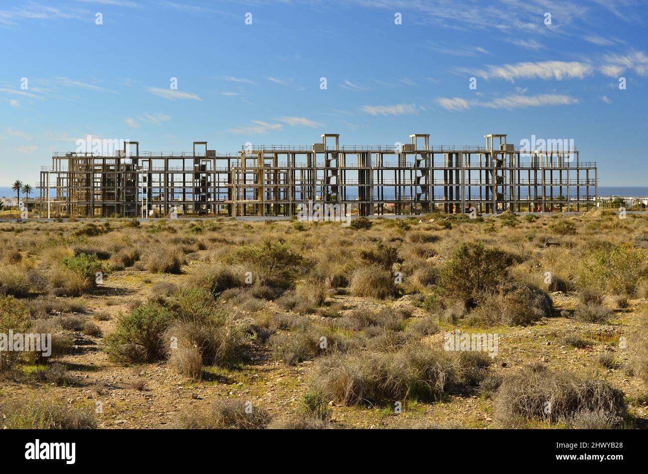 Unfinished property on the Mediterranean coast, abandoned after 2008 global financial crisis, arid grassy landscape of Almeria southern Spain. Stock Photo