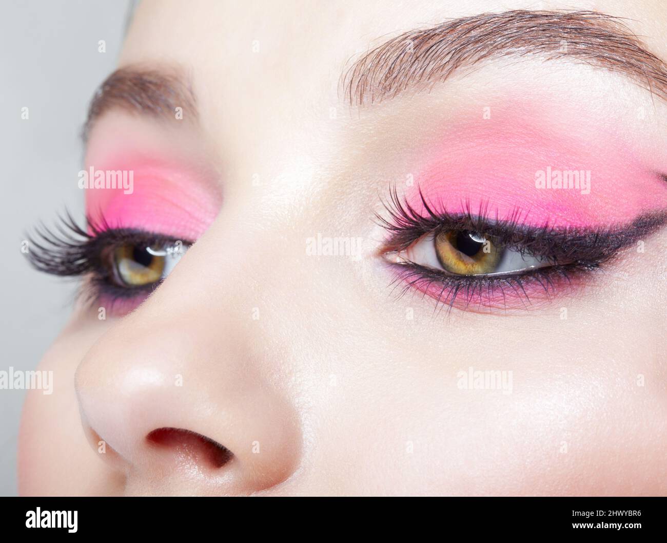 Closeup macro shot of human female face. Woman with an oriental appearance and pink eyes beauty makeup. Stock Photo