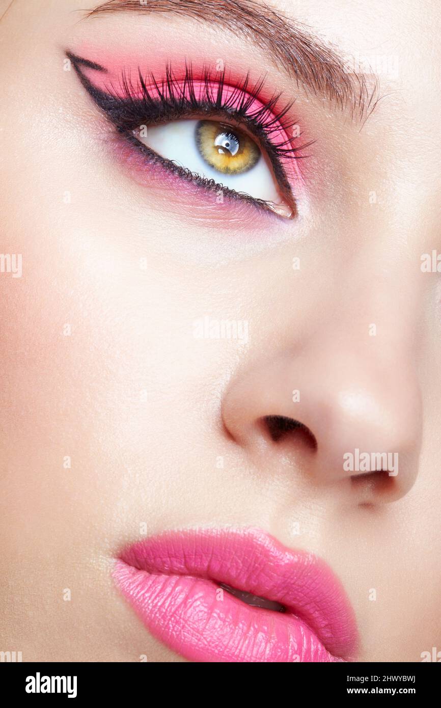 Closeup macro shot of human female face. Woman with an oriental appearance and pink eyes and lips beauty makeup. Stock Photo