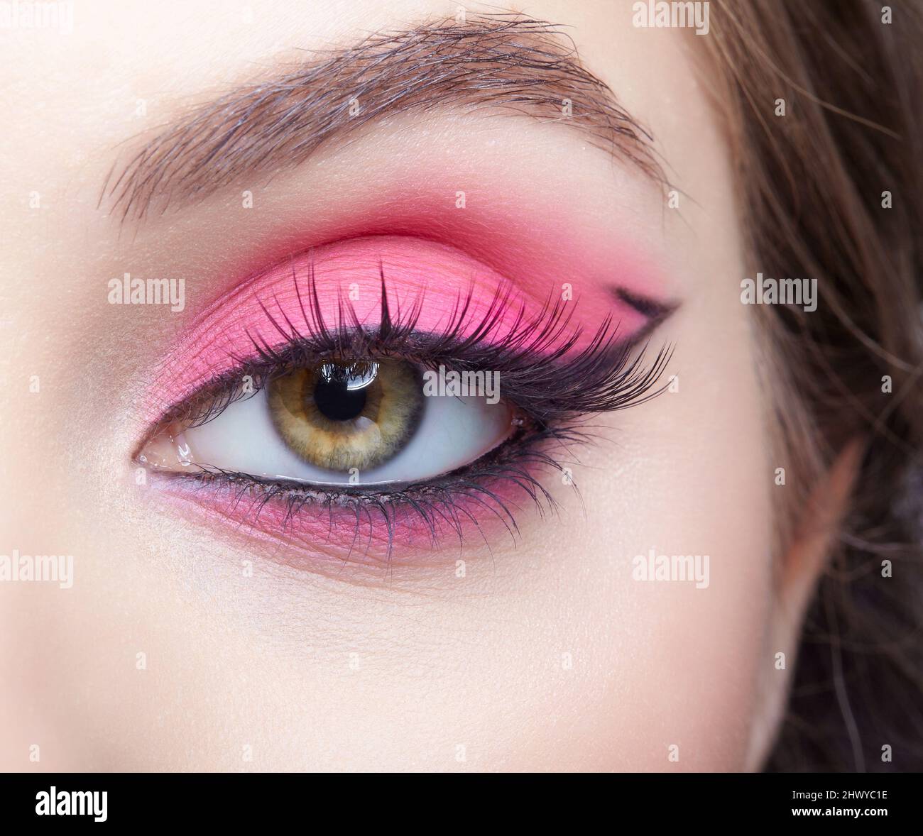 Closeup macro shot of human female eye. Woman with natural evening vogue face beauty makeup. Girl with perfect skin and pink eyes shadows. Stock Photo