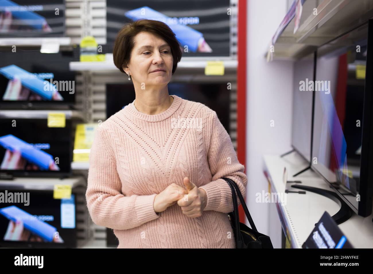 Mature woman choosing television in appliance store Stock Photo