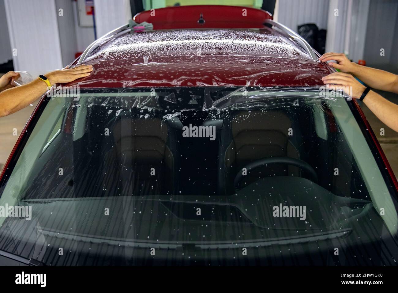Master man installs strip of vinyl film in risk zone of windshield to
