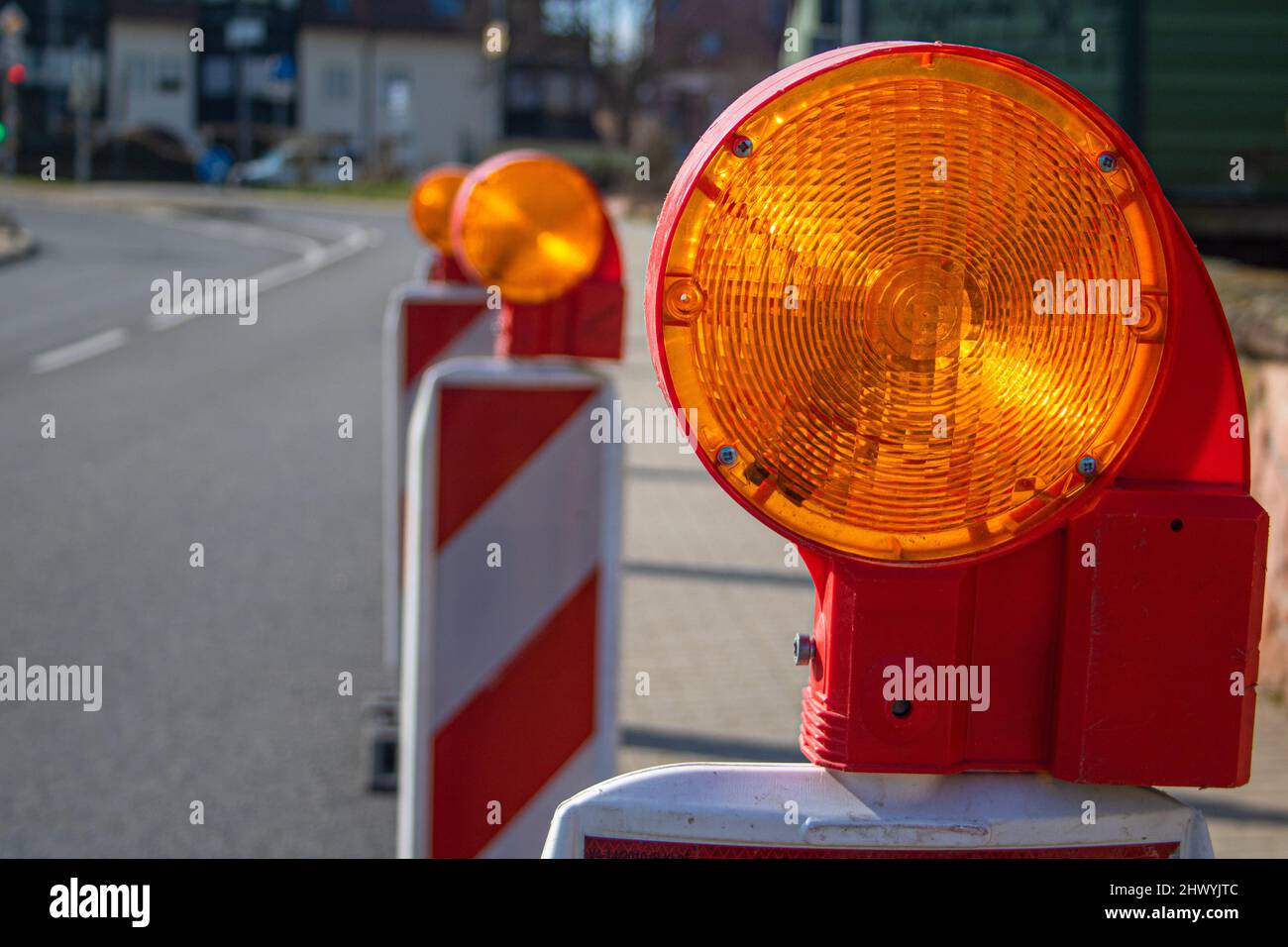 Street barricade with warning Flashing signal lamp on a road Construction site safety, blur site background Stock Photo