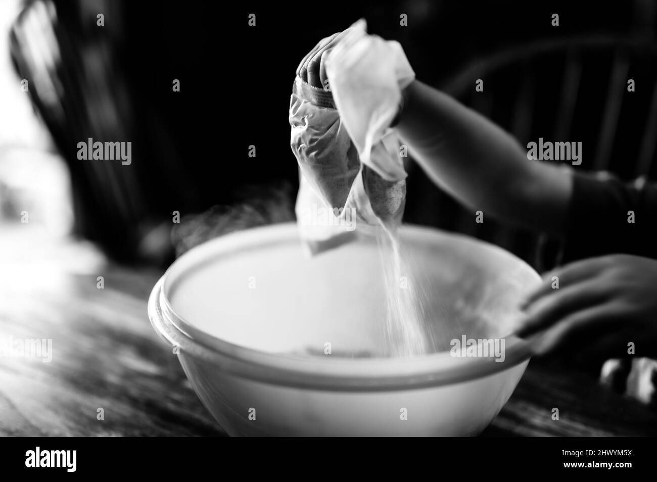 Little child dumping ingredients into a bowl causing dust to rise into the air. Stock Photo