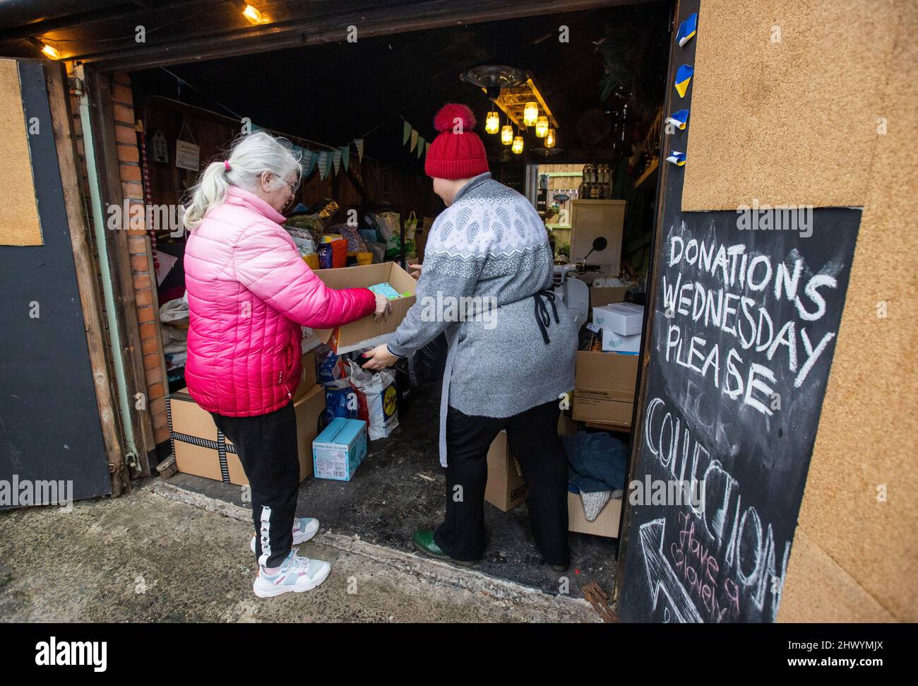 Smokey Deli owner Monika Rawson receiving a donation for the Ukrainian people by a member of the local community. Monika who has been living in Northern Ireland for over 16 years since moving from Poland has created a drop off point at her restaurant in east Belfast for donations to be sent to the Ukrainian people. Stock Photo