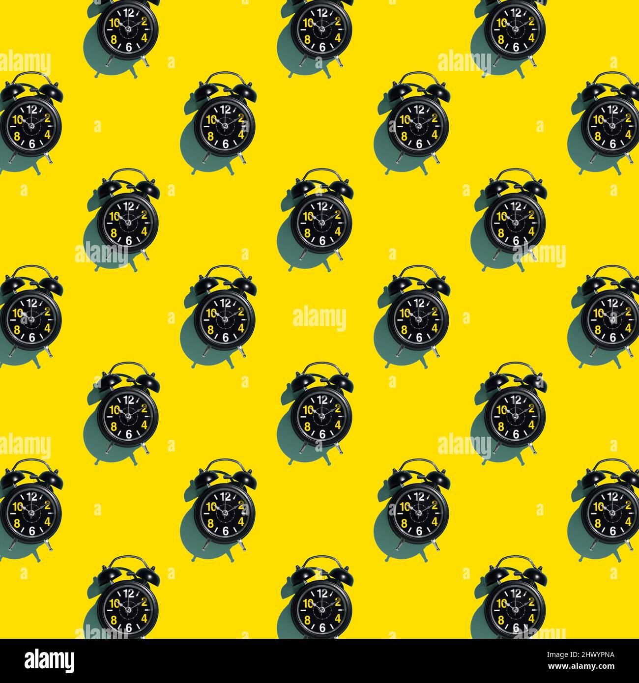 Pattern of black alarm clocks on yellow background. Timeout or execution time. Concept. Background. Stock Photo