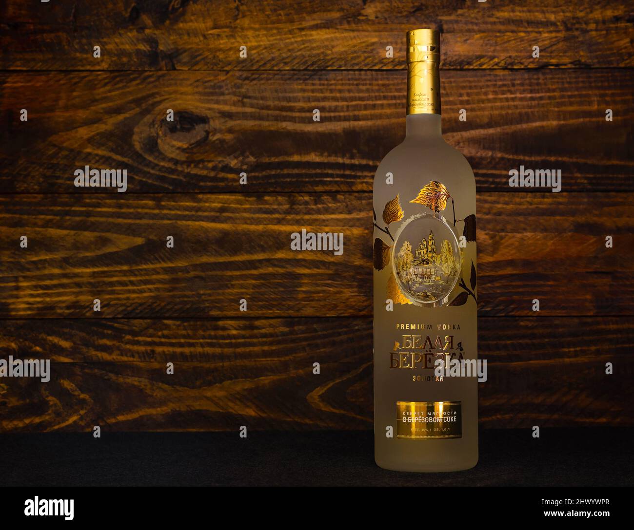 A bottle of Russian vodka Belaya Beryoka Golden on a dark wooden background. Vodka includes alcohol, birch sap, honey and sea buckthorn berries. Russi Stock Photo