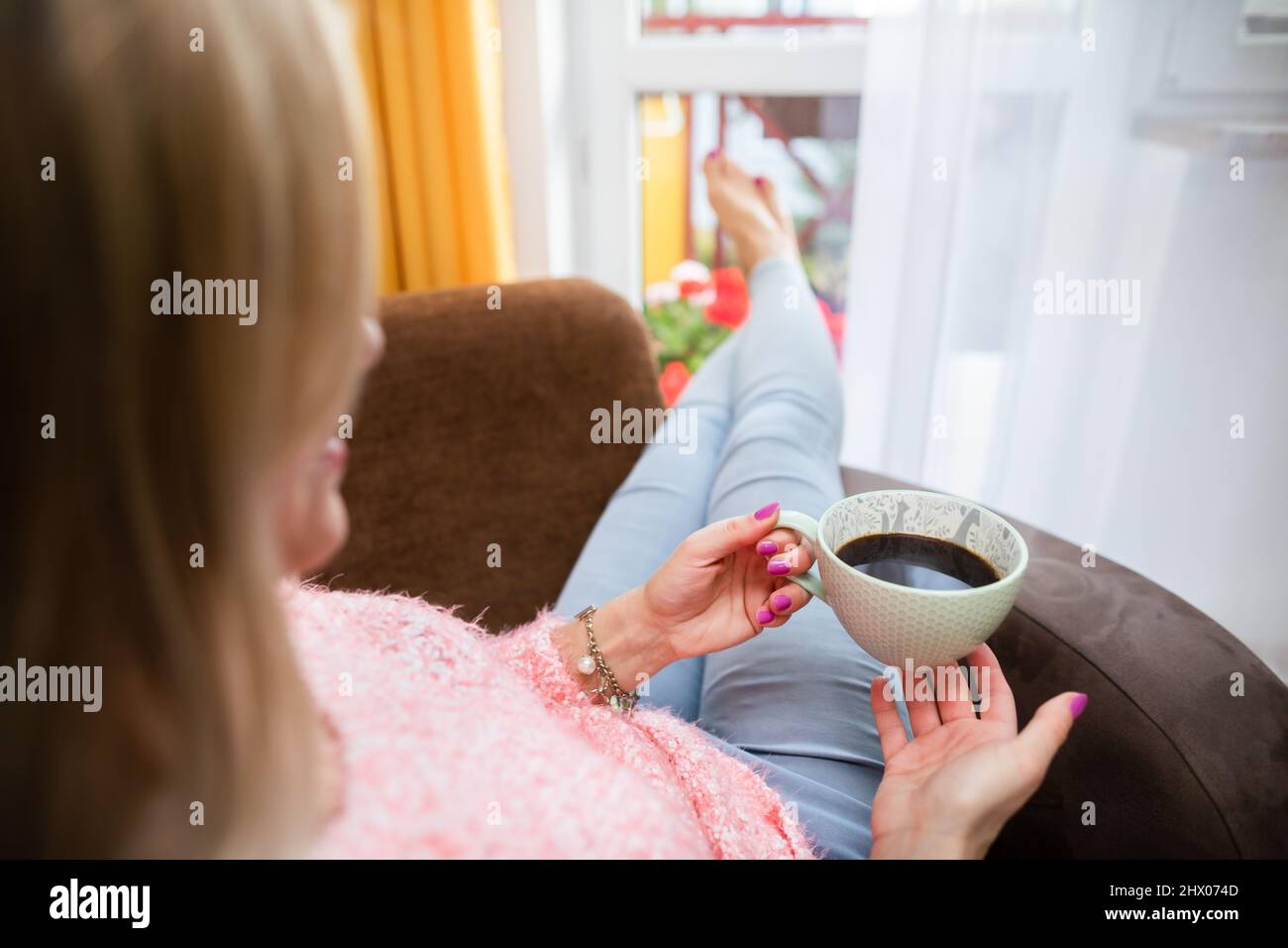 A young woman holds a cup and looks ahead. Stock Photo