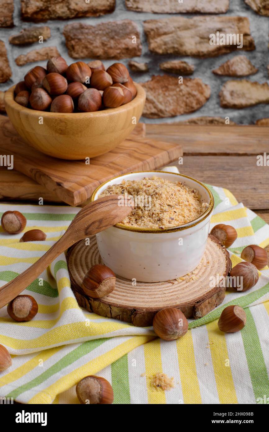 Raw Organic Ground Hazelnut Flour in a Bowl with whole nuts on rustic