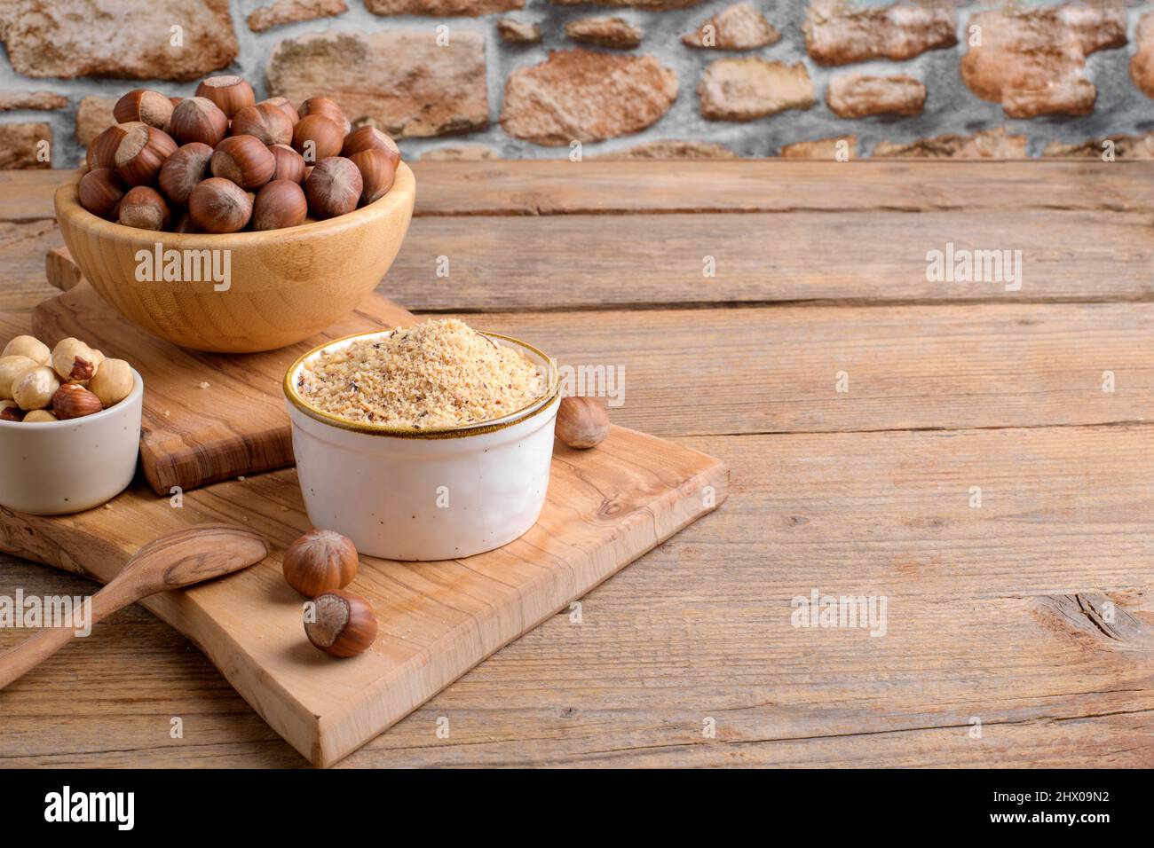 Raw Organic Ground Hazelnut Flour in a Bowl with whole nuts on rustic